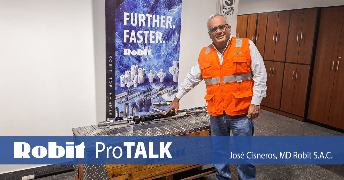 José Cisneros, Managing Director of Robit S.A.C., which is based in Lima, Peru, standing in front of a Robit drill hammer that has been cut open and placed on its delivery box, with a Robit drill bit poster on the background.