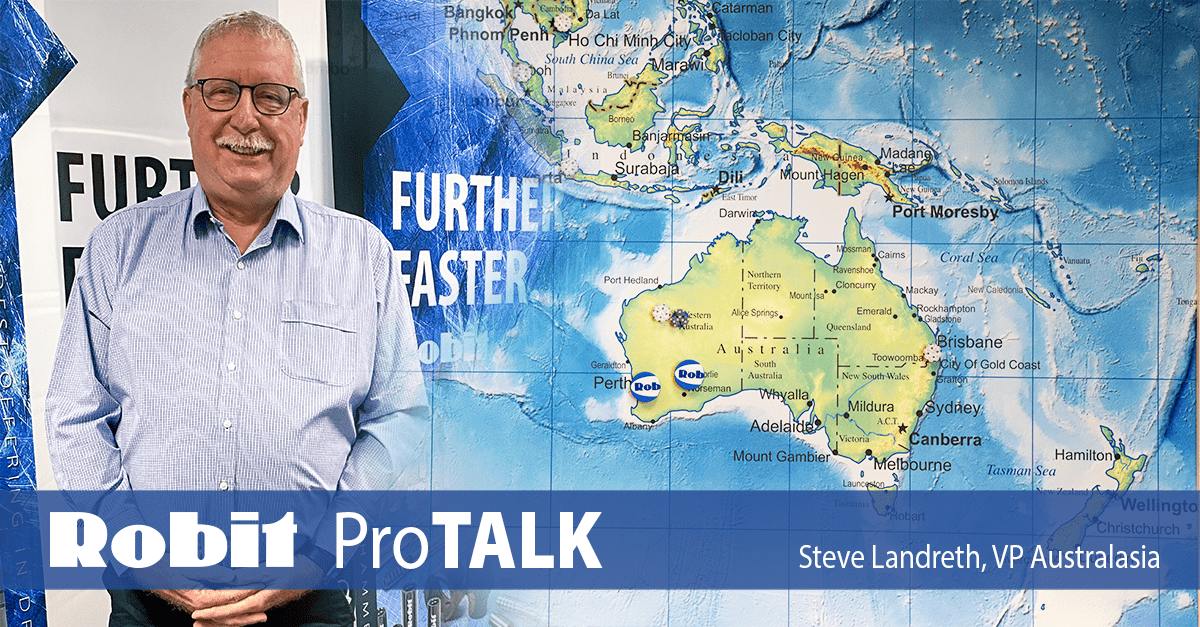 Steve Landreth, Robit's VP of Autralasia, standing in front of Robit drill bit posters, with a map of Australia affixed next to him, showing the drill sites in the area that use Robit drilling consumables.